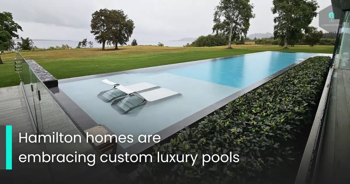 Modern infinity pool with lounge chairs overlooking a large green lawn in Hamilton.